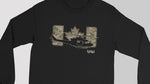 A black long-sleeve crewneck shirt featuring a graphic print of a military helicopter in front of a camouflage Canadian flag and the letters 'UH' with 'IYD1' underneath, shown on a neutral gray background.