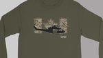 An olive green long-sleeve t-shirt with a graphic on the chest featuring a black helicopter silhouette, a camouflage Canadian maple leaf, and the text 'I Y O H I' in white.